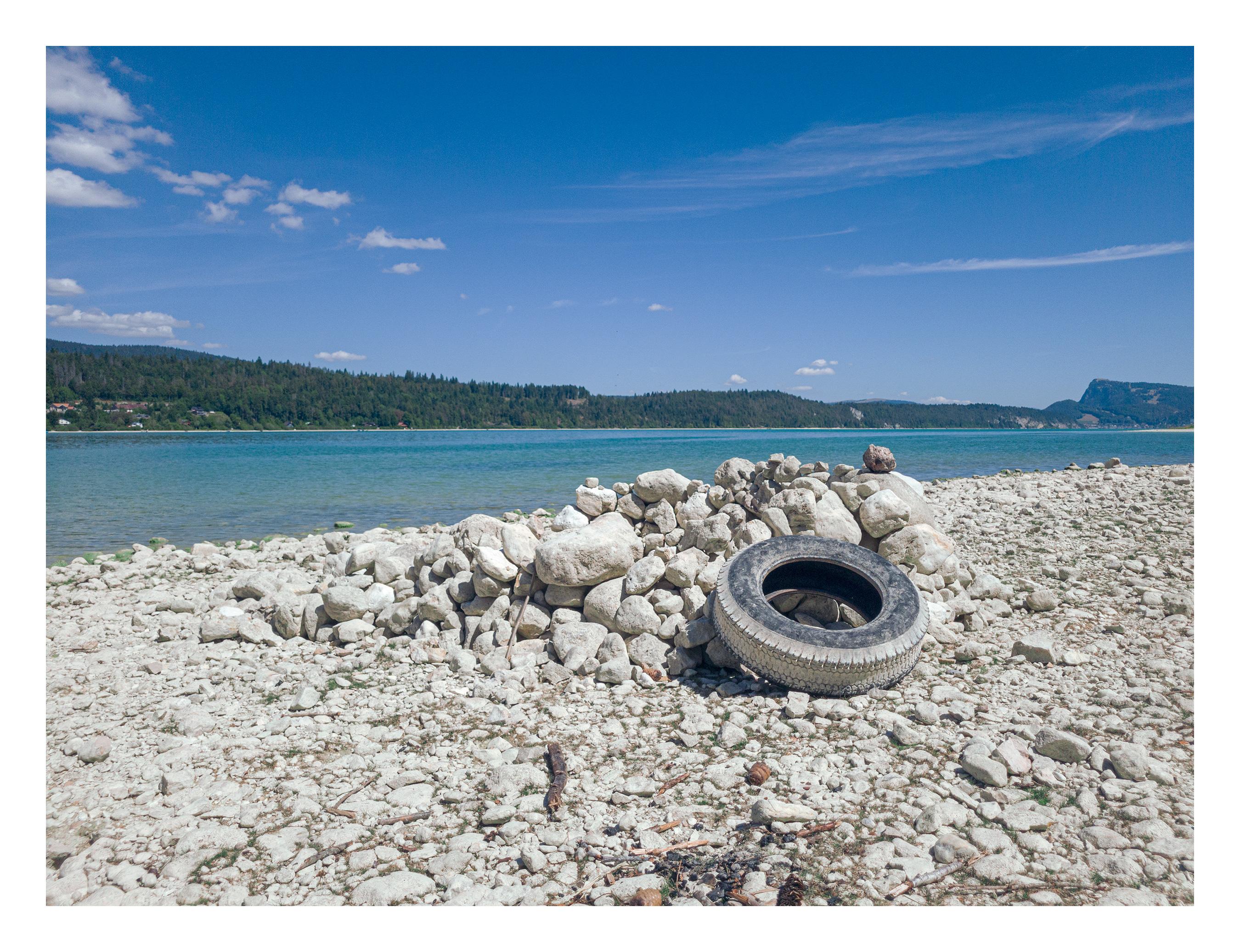 Un pneu abandonné au bord du lac de Joux. La Dent de Vaulion en arrière-plan